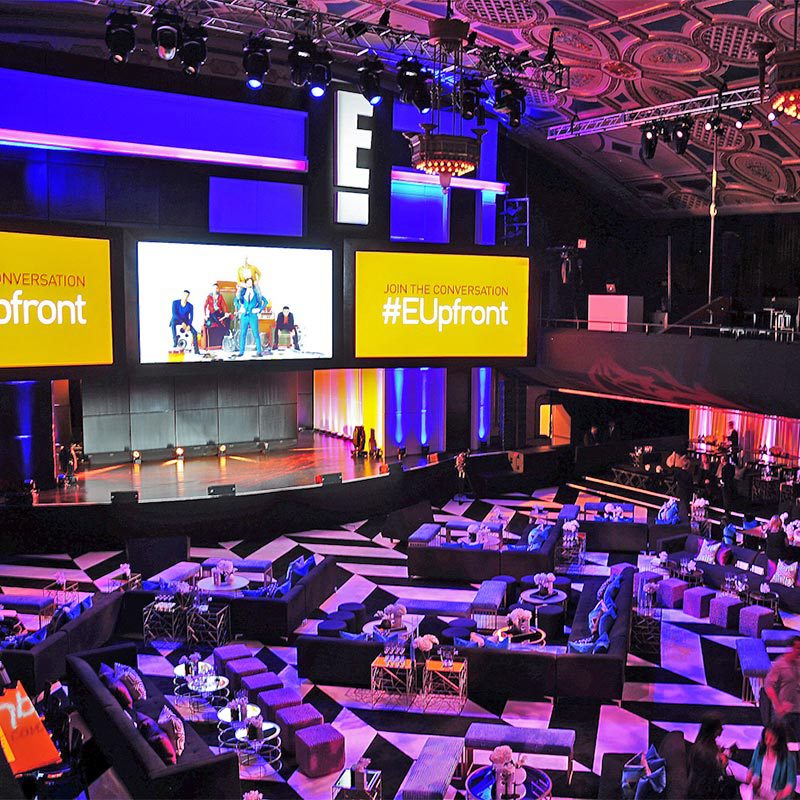 A spacious room filled with numerous individuals seated around, engaged in conversation and interaction.